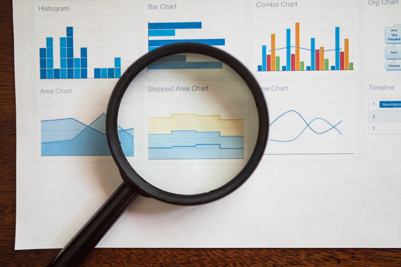 home-services-02 A magnifying glass focuses on various business charts and graphs on paper.